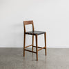 angled view of the savanna bar stool with vintage brown wood and black leather seat from Corcovado