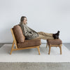 corcovado armless leather look chair with footstool and a lady sitting on it with her feet up on the footstool