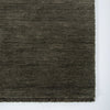 corner image of the forest green wool floor rug with small fringing detail from corcovado