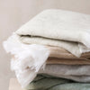 pile of sorrento wool blend throws in an off-white colour